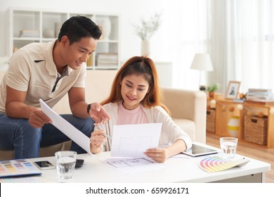 Portrait Of Young Asian Family Discussing Interior Design Smiling While Planning New House