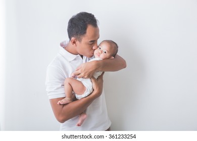 A Portrait Of A Young Asian Father Holding And Kissing His Adorable Baby On White Background