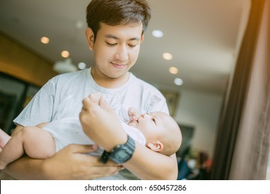 Portrait Of Young Asian Father Holding His Newborn Baby Son At Home.