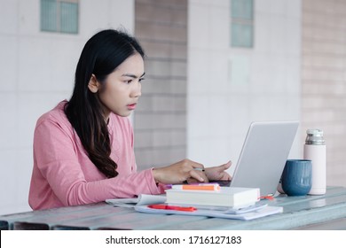 Portrait Of A Young Asian Female Adult Learner Studying Online At Home During Corona Virus Or COVID-19  Pandemic. Businesswoman Work With Laptop At Home In House Corridor And Garden.