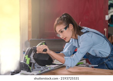 Portrait Young Asian Female Carpenter Using Electric Saw Cutting Wood In Carpentry Wood Working Shop