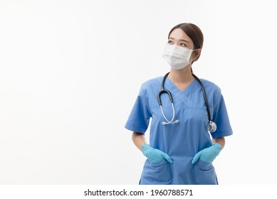 Portrait Of Young Asian Female Doctor Wearing Medical Facemask, Gloves And Stethoscope, Look Up And Thinking, Isolated On White Backround, Covid-19 Concept