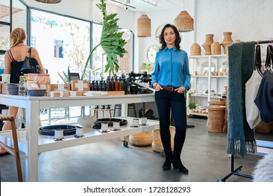 Portrait Of A Young Asian Female Entrepreneur Standing By A Table Display In Her Trendy Shop