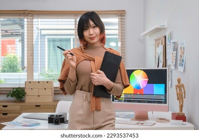 Portrait of young asian female graphic designer in stylish clothes holding graphic tablet standing at creative office. - Powered by Shutterstock