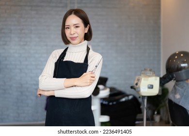 Portrait of a young asian female hairdresser holding qualified haircut tools in her salon for a woman's haircut. Photo job concept for small business owner and haircare. - Powered by Shutterstock