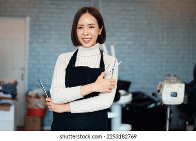 Portrait of a young asian female hairdresser holding qualified haircut tools in her salon for a woman's haircut. Photo job concept for small business owner and haircare. - Powered by Shutterstock