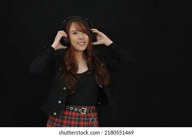 Portrait Young Asian Female Singer Wearing  Headphones, Attractive Cheerful Girl Standing Isolated On Black Background .soft Focus