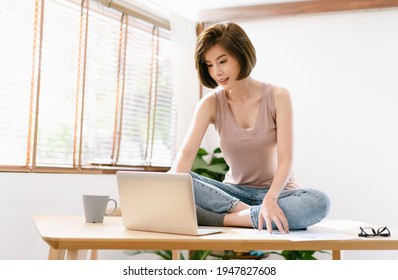 Portrait Of Young Asian Freelancer Woman Using Laptop Computer Sitting On Desk At Home. Online Freelancer Job, Smiling Happy,browse Internet, Small Business Owner Sme Concept. Workplace In Living Room