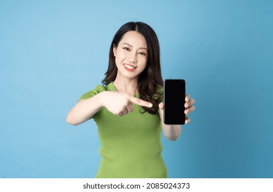 Portrait Of Young Asian Girl, Holding Phone, Isolated On Blue Background