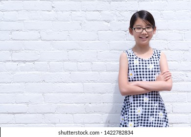 Portrait of young Asian girl teen wearing eyeglasses against white brick wall