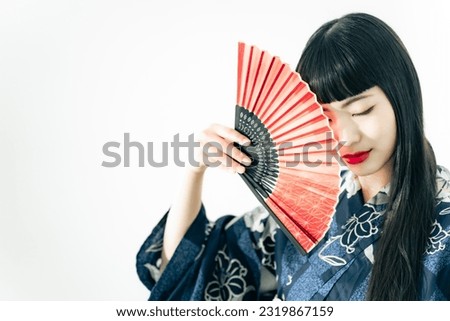 Portrait of young Asian girl wearing Yukata with oriental fan. Japanese traditional summer dress.