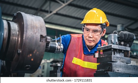 Portrait Of A Young Asian Industrial Worker Using Measuring Tool On The Machine.