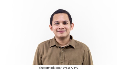 A portrait of young Asian Malay man with brown casual shirt and short hair smiling at the camera with isolated white background.