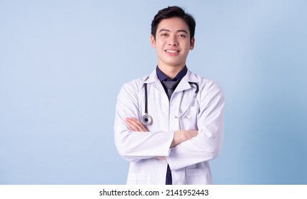 Portrait of young Asian male doctor on blue background