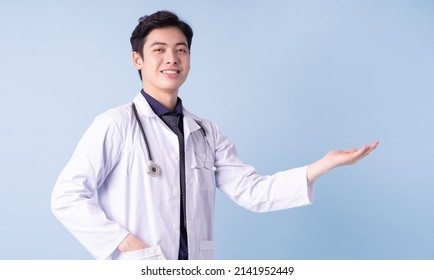 Portrait of young Asian male doctor on blue background