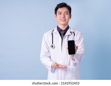 Portrait Of Young Asian Male Doctor On Blue Background