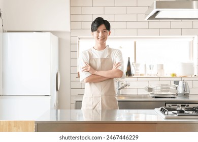 portrait of young asian man in apron relaxing in kitchen - Powered by Shutterstock