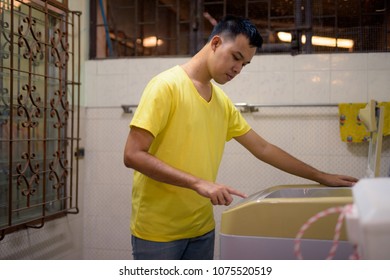 Portrait Of Young Asian Man Doing House Chores At Home