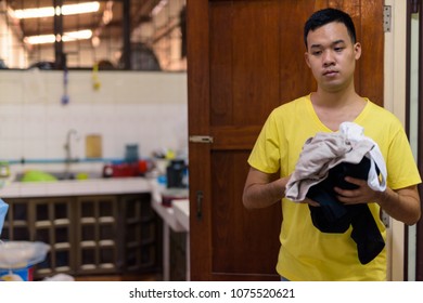 Portrait Of Young Asian Man Doing House Chores At Home