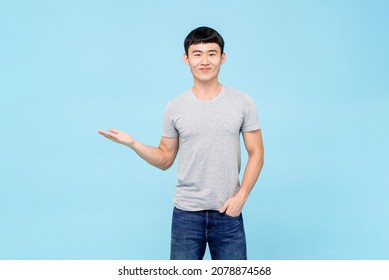 Portrait Of Young Asian Man With Hand Opening In Isolated Blue Studio Background