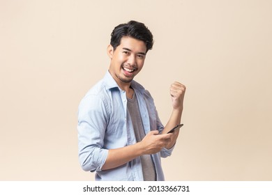 Portrait young Asian man handsome happy smile in formal shirt using smartphone trading or chatting on brown isolated studio background.