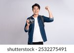 Portrait of young Asian man holding travel camera and posing on white background