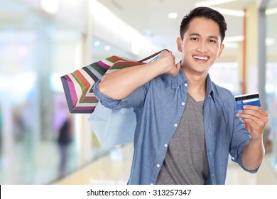 A Portrait Of A Young Asian Man Holding Shopping Bags And Credit Card, Close Up