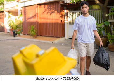 Portrait Of Young Asian Man Taking Out The Garbage At Home