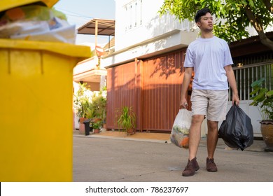 Portrait Of Young Asian Man Taking Out The Garbage At Home