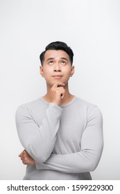 A Portrait Of A Young Asian Man Thinking Looking Up Isolated Over White Background