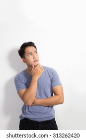 A Portrait Of A Young Asian Man Thinking Looking Up Isolated Over White Background