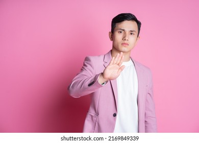 Portrait of young Asian man wearing pink suit posing on background