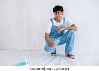 Portrait Young Asian Man In White Shirt With Bear Suit Sit And Painted Plot On Hand And Look At Camera In White Wall, Renovation Concept,