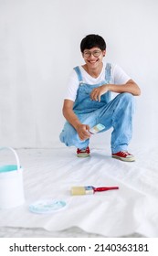 Portrait Young Asian Man In White Shirt With Bear Suit Sit And Painted Plot On Hand And Look At Camera In White Wall, Renovation Concept,