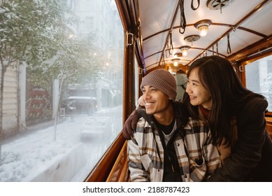 Portrait of young asian man and woman looking at the snow through train window. couple passenger riding classic train during their trip in turkey