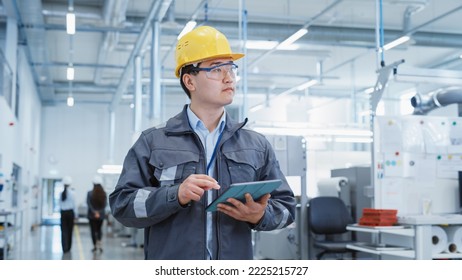 Portrait of a Young Asian Man, Working as an Engineer at a Industrial Facility, Wearing Work Jacket and a Yellow Hard Hat. Heavy Industry Specialist Walking and Using Tablet Computer. - Powered by Shutterstock