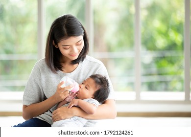 Portrait Young Asian mother nursery feeding bottle of baby milk to newborn baby in mother embracing. Health care single mom motherhood stressful concept.