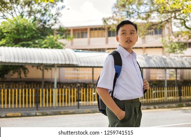 Portrait Of A Young Asian Student In Standard Uniform, Chinese Ethnicity, Standing Near The School Compound, Looking Towards Future, Thinking Of His Ambition. Concept Of Education With Copy Space