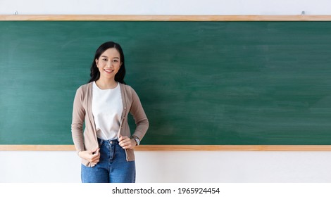 Portrait Of A Young Asian Teacher Smiling Happily In Front Of The Classroom. Close Up Women Student Looking At Camera On Blackboard. Back To School Concept