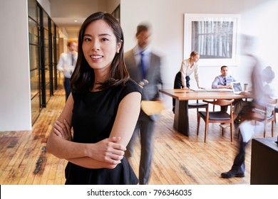 Portrait Of Young Asian Woman In A Busy Modern Workplace