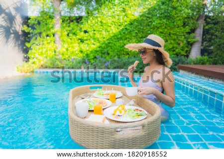 Portrait young asian woman happy smile enjoy with floating breakfast tray in swimming pool in hotel resort
