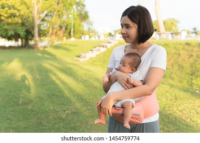 Portrait Of Young Asian Woman Holding Newborn Baby Girl With Hip Seat Outdoor Park. Adorable Baby And Mom Playing In Park Together. Happy Loving Family. Joy And Nature. Baby Tools.