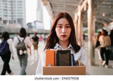 Portrait Of Young Asian Woman Holding Box Of Items After Being Laid Off From Job Due To Recession And Economic Stress In Industry