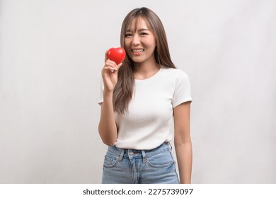 A Portrait of young asian woman holding holding red heart shape over white background studio
