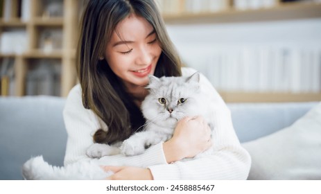 Portrait of young Asian woman holding cute cat. Female hugging her cute long hair kitty. Adorable pet concept - Powered by Shutterstock