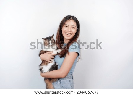 Portrait of young Asian woman holding cute angora cat with yellow eyes. Female hugging her cute long hair kitty isolated by white background. Adorable domestic pet concept.