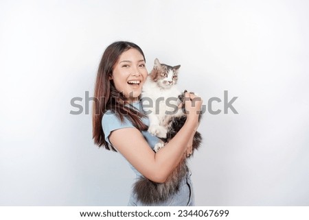Portrait of young Asian woman holding cute angora cat with yellow eyes. Female hugging her cute long hair kitty isolated by white background. Adorable domestic pet concept.