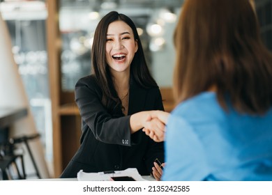 Portrait young Asian woman interviewer and interviewee shaking hands for a job interview .Business people handshake in modern office. Greeting deal concept - Shutterstock ID 2135242585