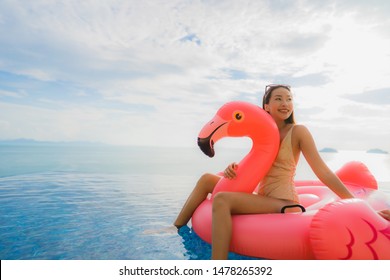 Portrait young asian woman on inflatable float flamingo around outdoor swimming pool in hotel resort for holiday vacation concept