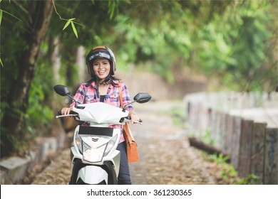 A Portrait Of A Young Asian Woman Riding A Motorcycle In A Park